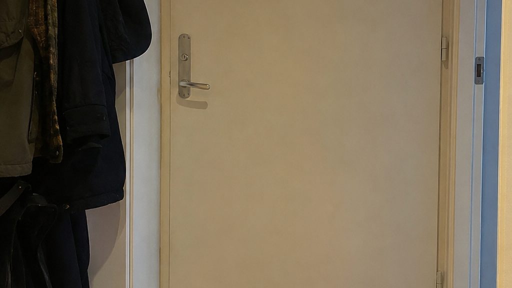 The inside of a flat front door with coats hanging beside it